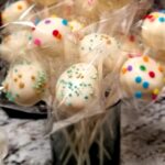 A bouquet of cake pops decorated with sprinkles, standing up in a short glass.